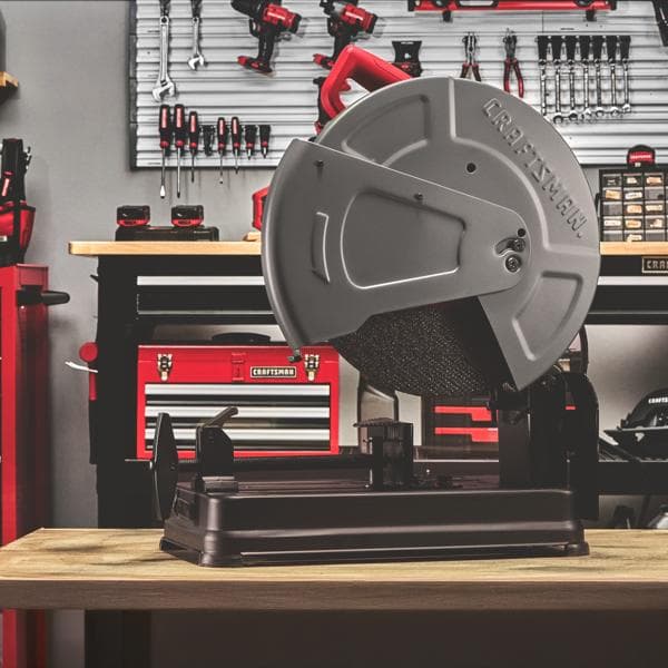 Craftsman CMEM2500 metal cutting saw with gray blade guard, shown on workbench in workshop setting.