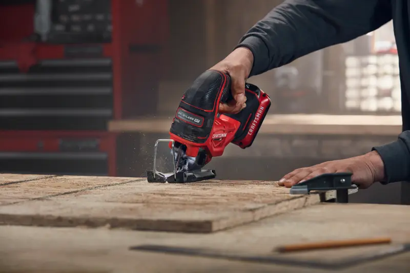 Photo of Craftsman cordless jigsaw CMCS650B cutting wood, close-up view in workshop setting.