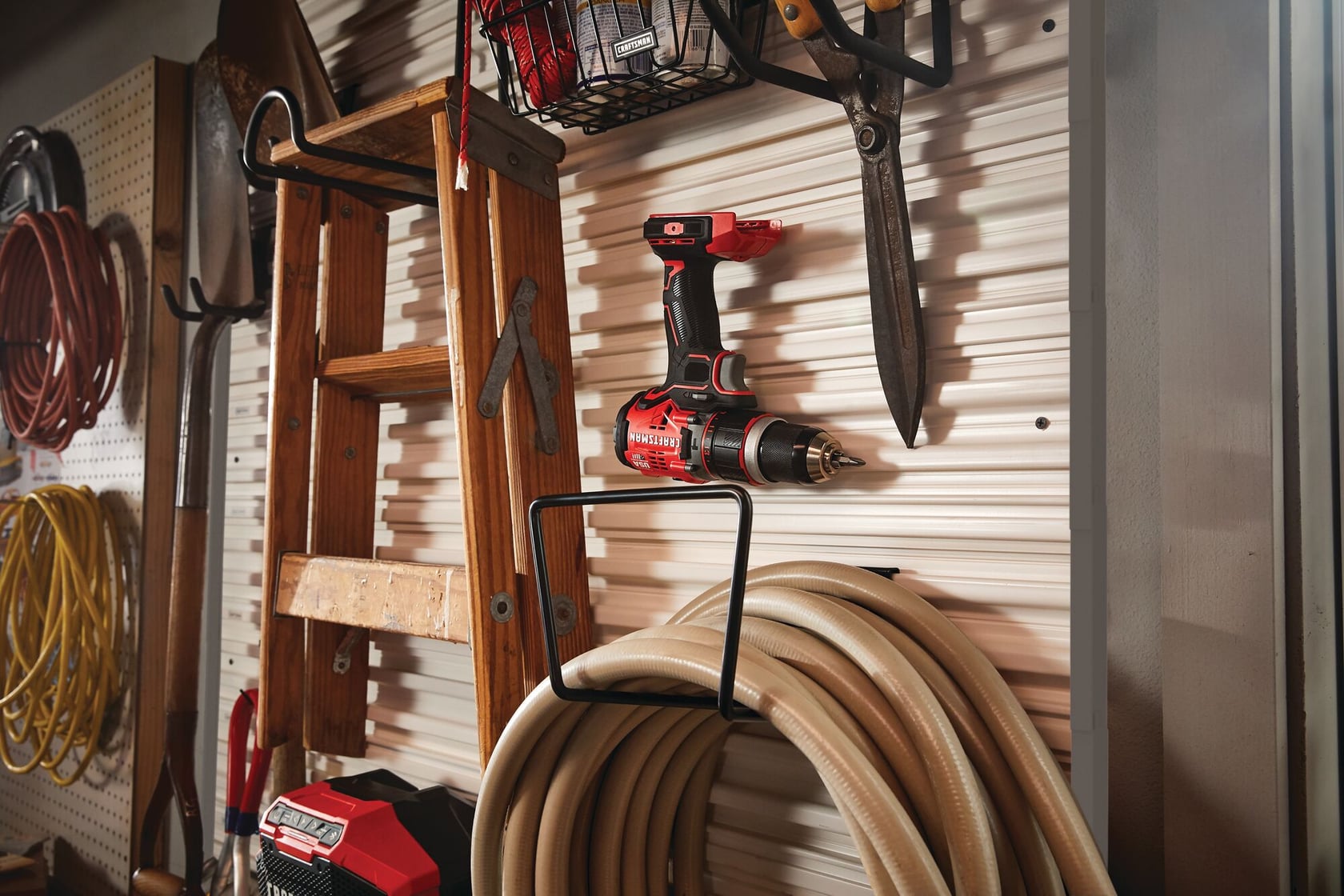 CRAFTSMAN CMST22000 wall-mounted hook holding a coiled hose and power drill in a garage storage setup.