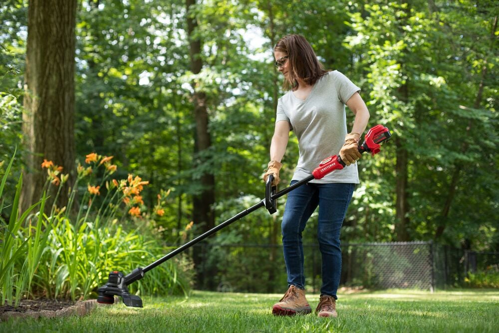 Photo of Craftsman CMCST930P1 string trimmer being used outdoors to edge grass near flower beds.