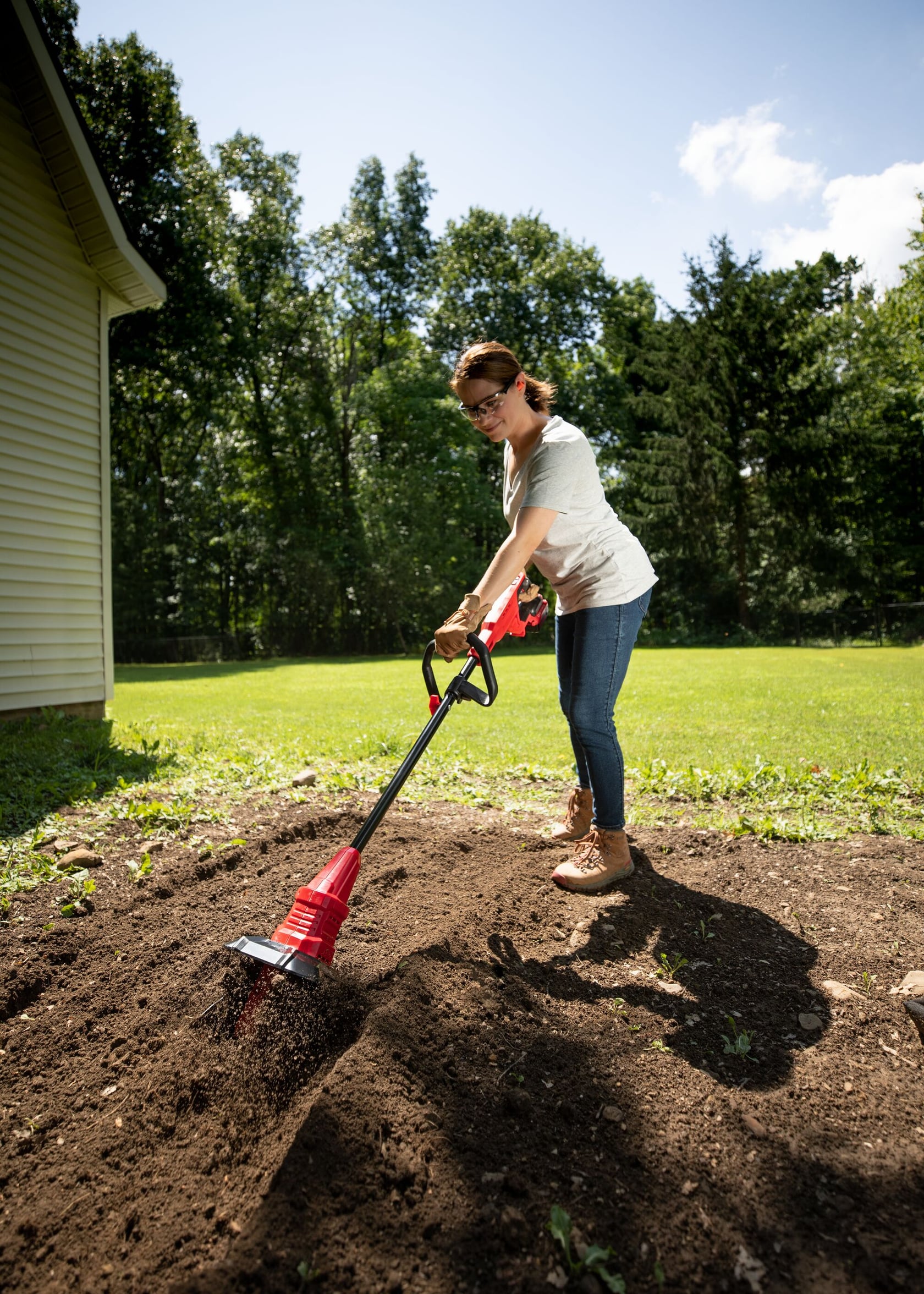 Photo of CRAFTSMAN cordless cultivator CMCTL320B in use in a garden, person tilling soil outdoors.