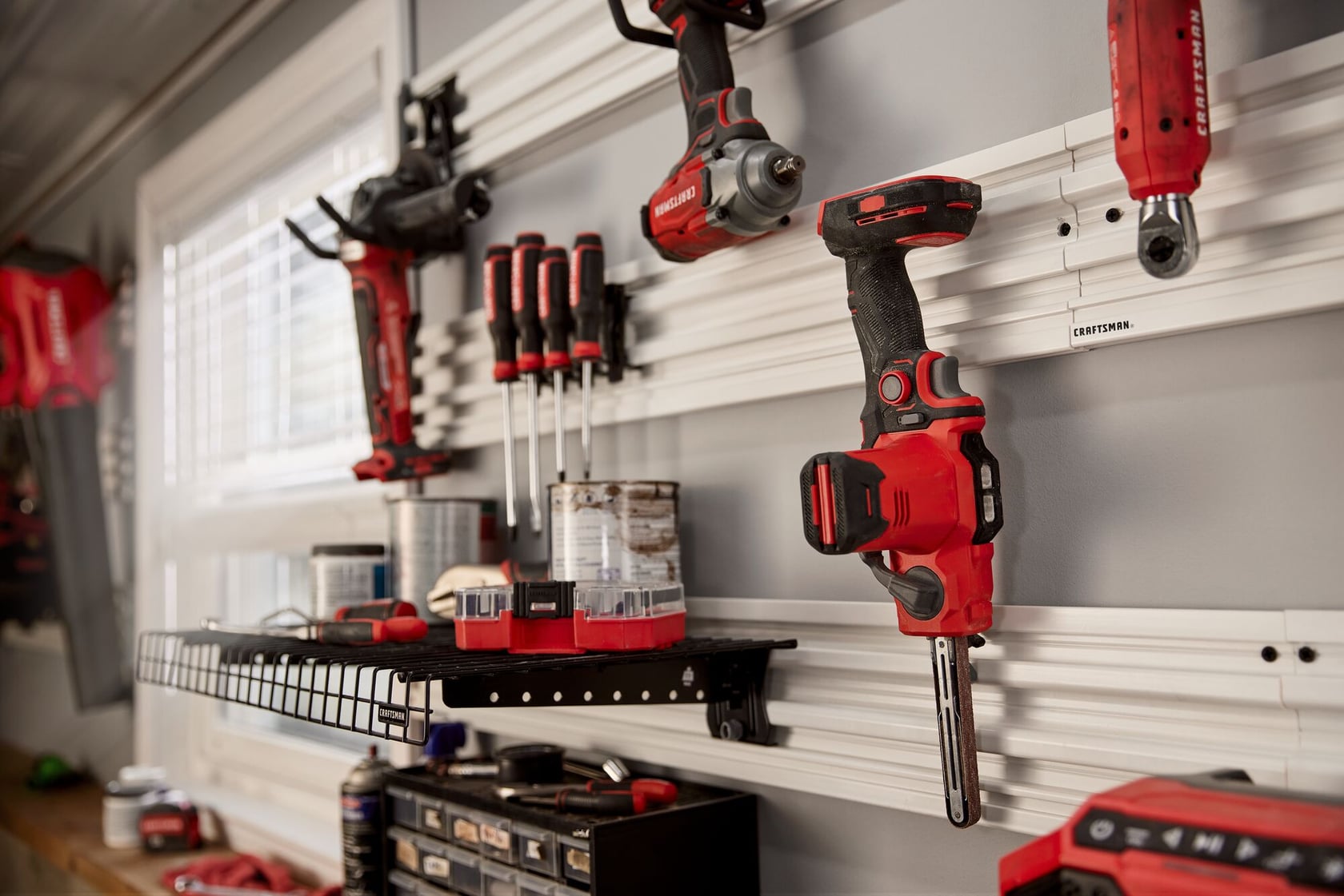 Photo of Craftsman belt sander CMCW211B on wall-mounted tool storage rack with other red tools.
