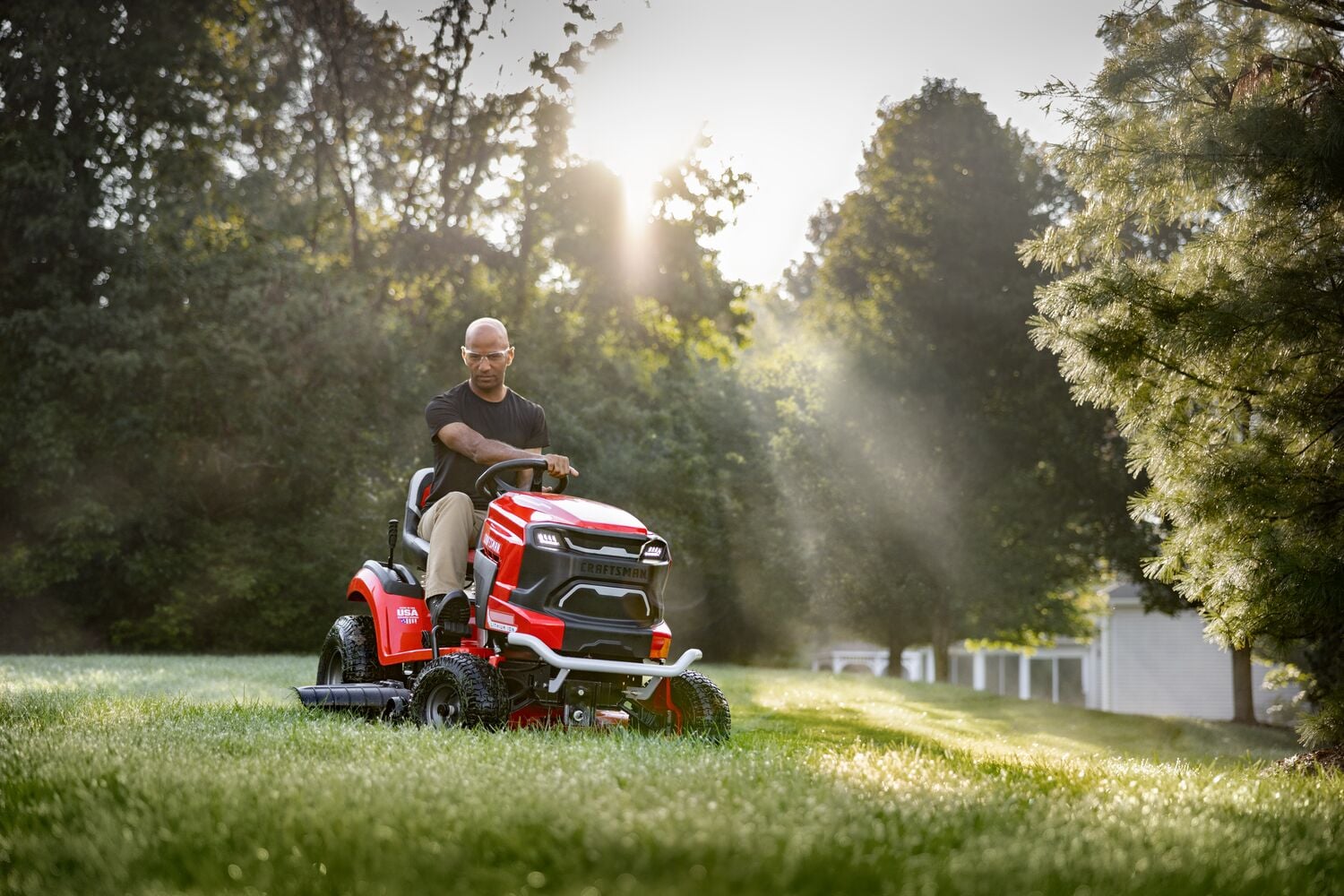 CRAFTSMAN Battery-Powered Riding Mower mowing background with woods and fence in background