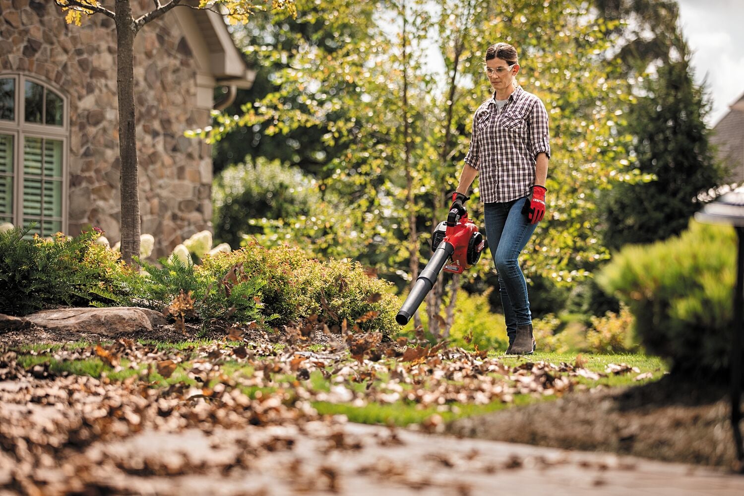 25 C C 2 cycle gas leaf blower being used by a person outdoors.