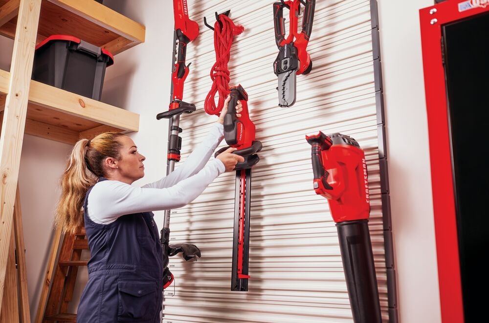 Person takes off lawn equipment hung on Versa Track 5 and 5 tenths inch White Composite Multipurpose Storage Rail System.