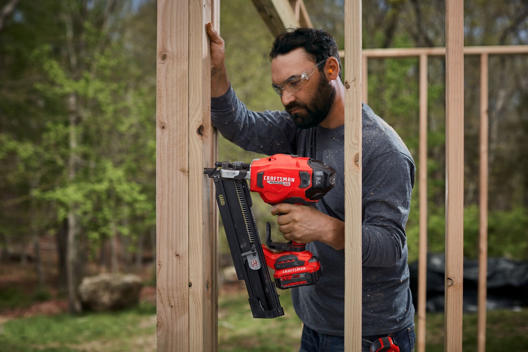 20 volt brushless cordless 21 degree plastic collated framing nailer being used by a person to nail wood bars.