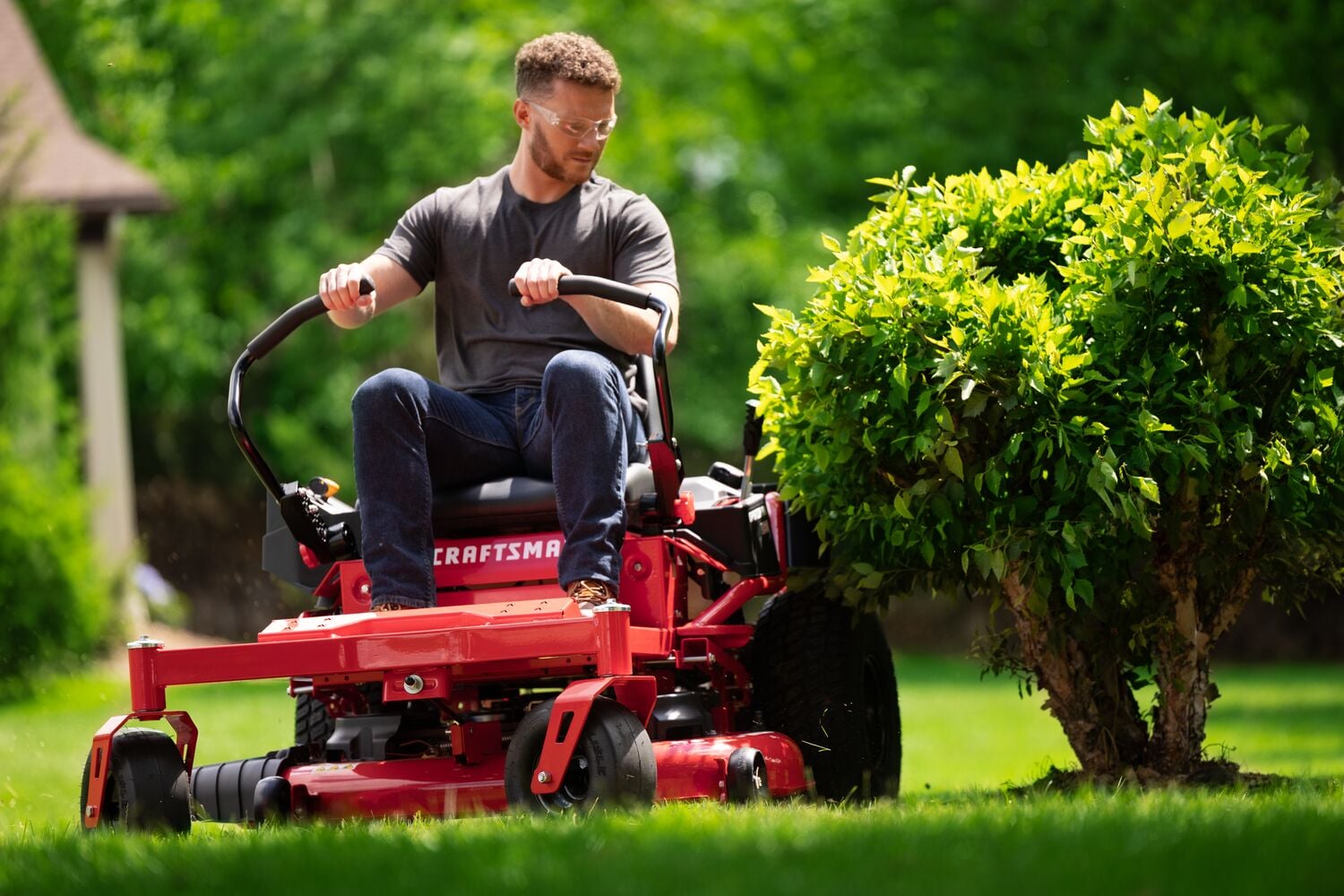 Man riding CRAFTSMAN Z3200 Gas Zero-Turn around bush