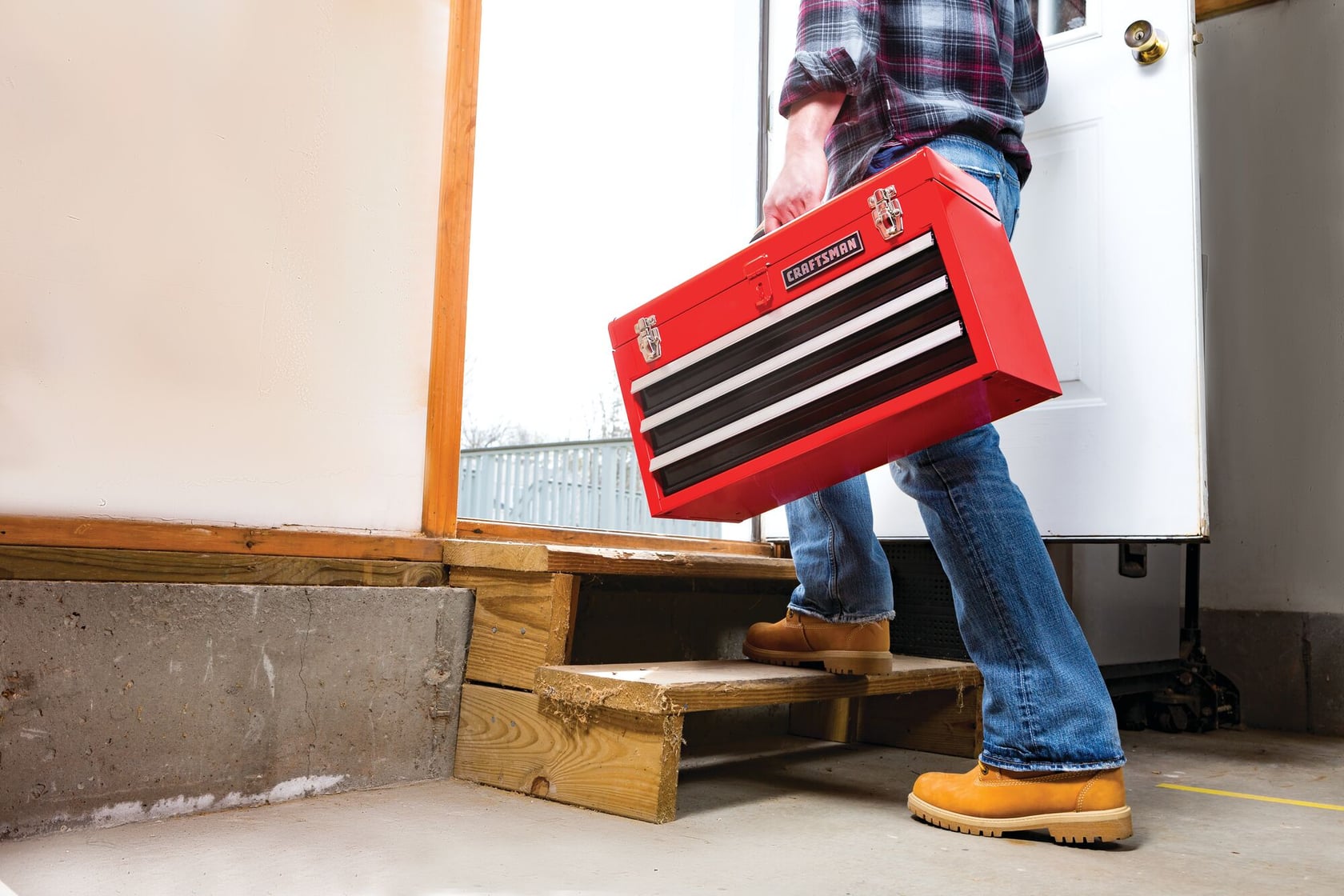 Portable 20 and 5 tenths inch Ball bearing 3 Drawer Red Steel Lockable Tool Box being carried by person towards work site.