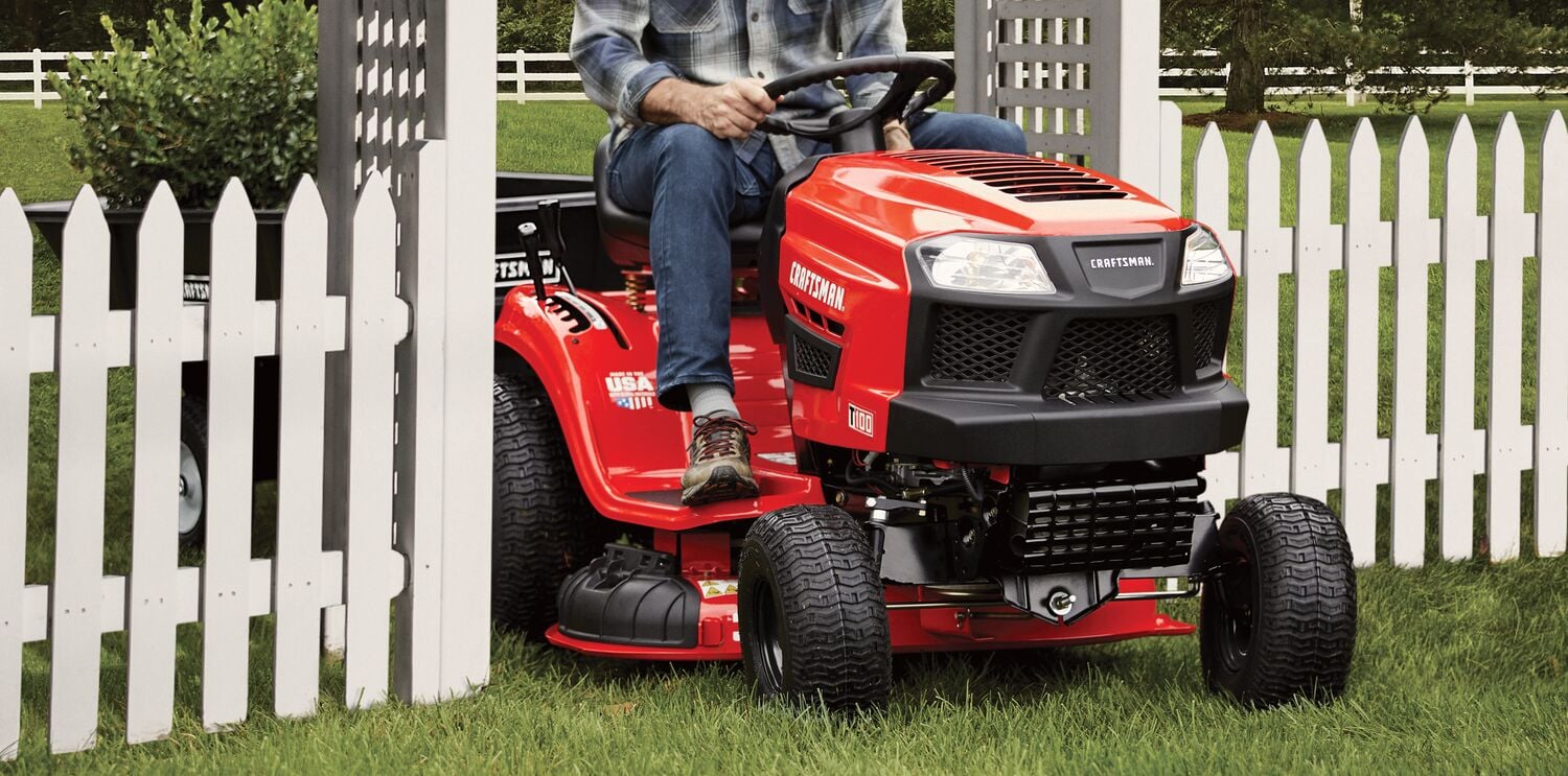 CRAFTSMAN T100 36 In. 11.5 Hp* Gear Drive Riding Mower mowing between fence gate wearing jeans and plaid