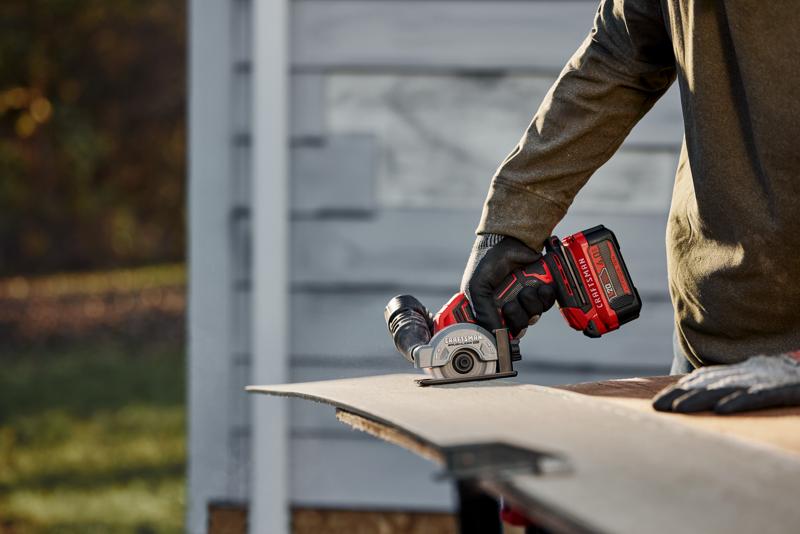 Photo of a person using a Craftsman compact saw CMCM300B to cut a sheet material outdoors.