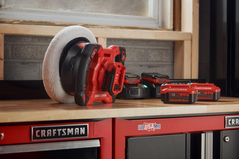 Photo of Craftsman CMCE100B cordless polisher with red and black body on workshop table, batteries visible.