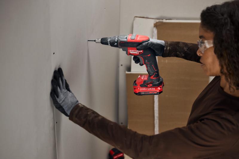 Photo of a person using a Craftsman cordless drill CMCF600B to drive screws into drywall.