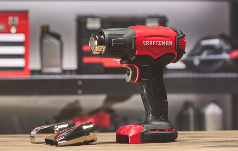 Photo of Craftsman CMCE530B cordless heat gun with two metal nozzle attachments on table, red and black design.