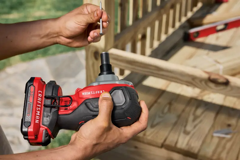 Photo of Craftsman cordless impact driver CMCN150B held near wood assembly outdoors.