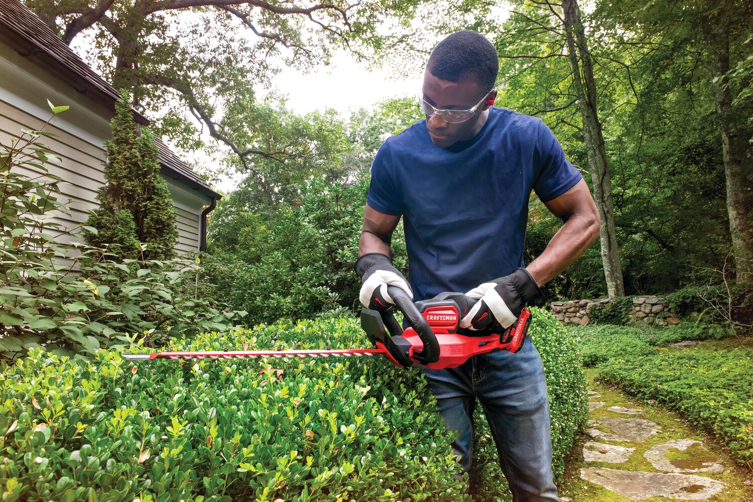 Cordless 22 inch hedge trimmer being used to level hedge by person.