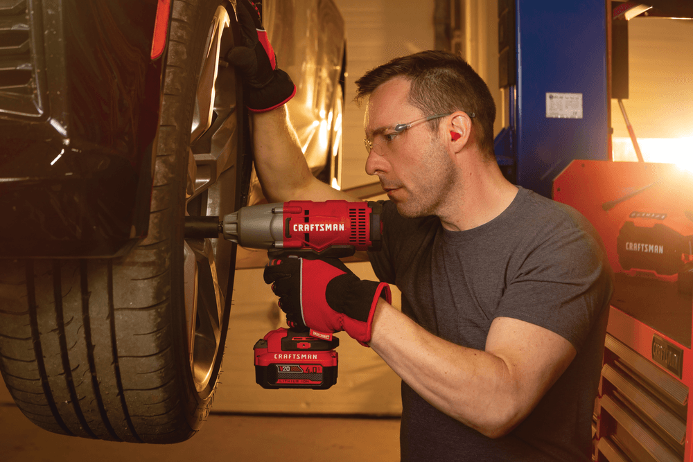 Cordless half inch impact wrench kit 1 battery being used to tighten tyre screws by person.