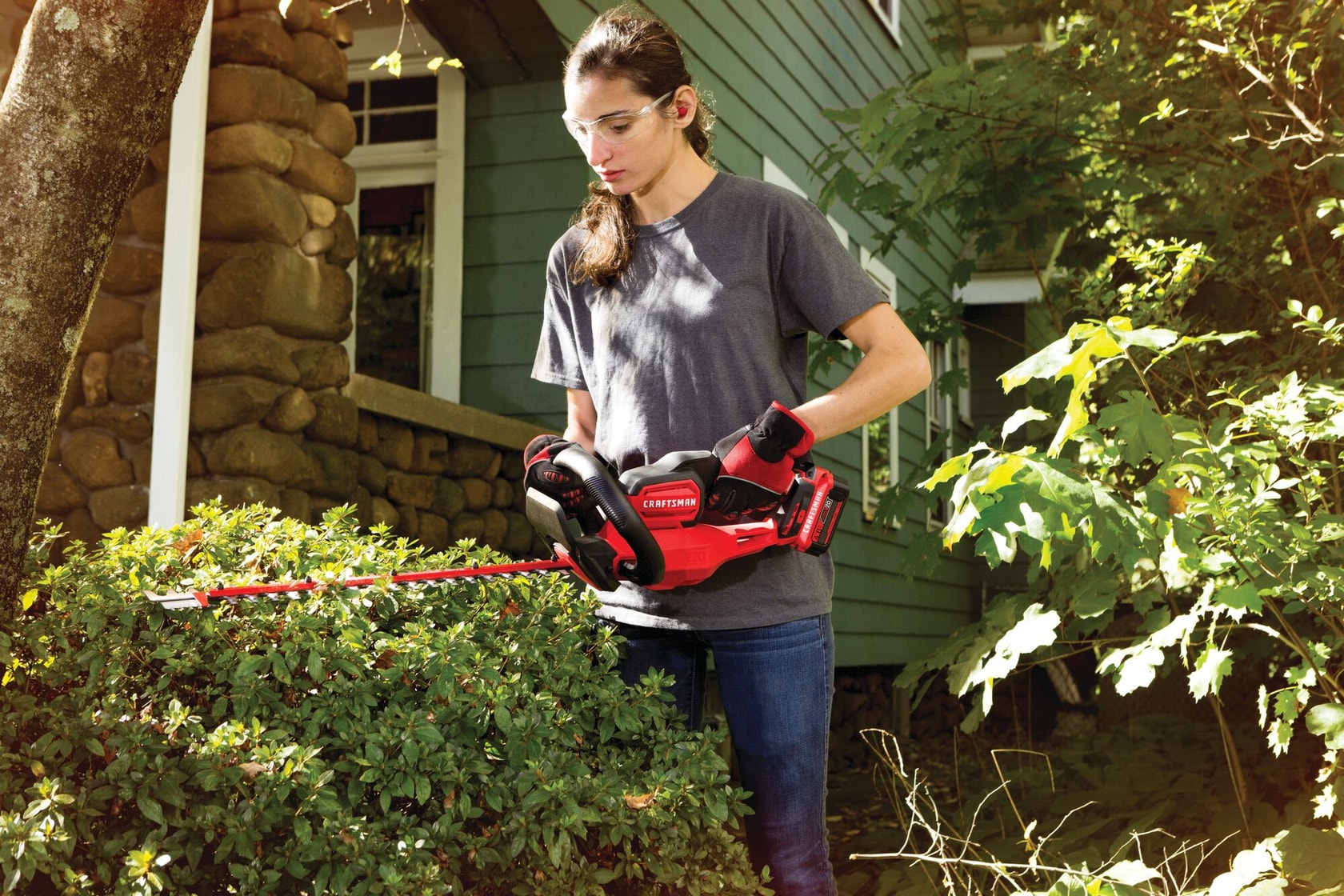Cordless 22 inch hedge trimmer being used to trim bushes.