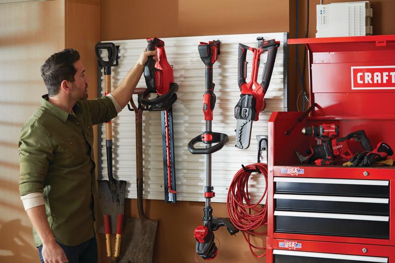 Cordless 22 inch hedge trimmer kit 2 ampere hours hanged in garage.