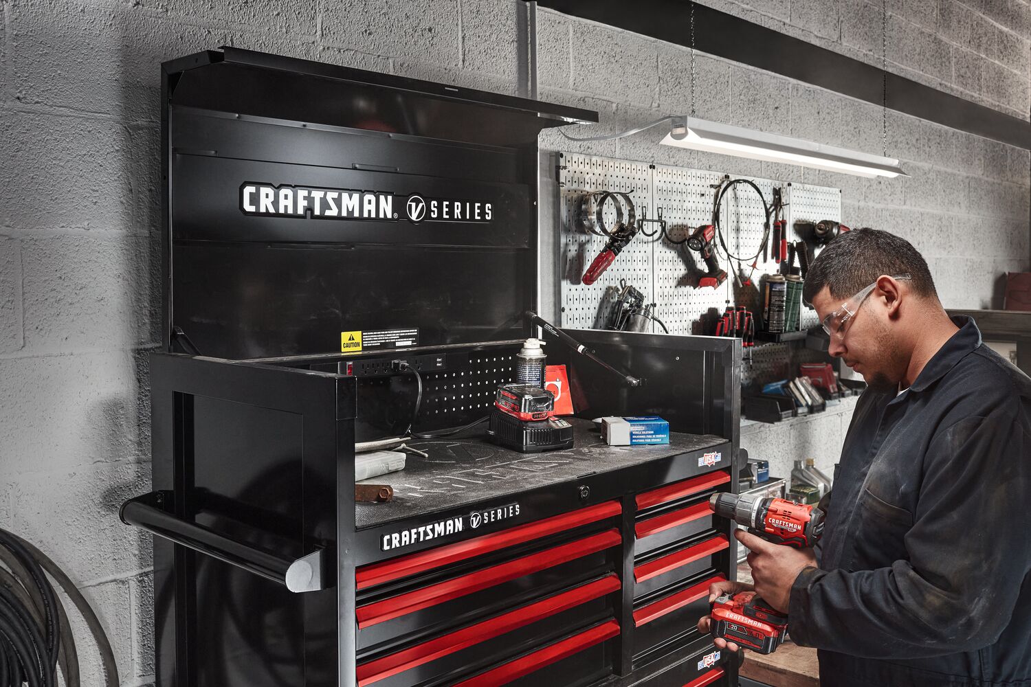 Mechanic working in automotive shop filled with various CRAFTSMAN V-Series™ storage and tools