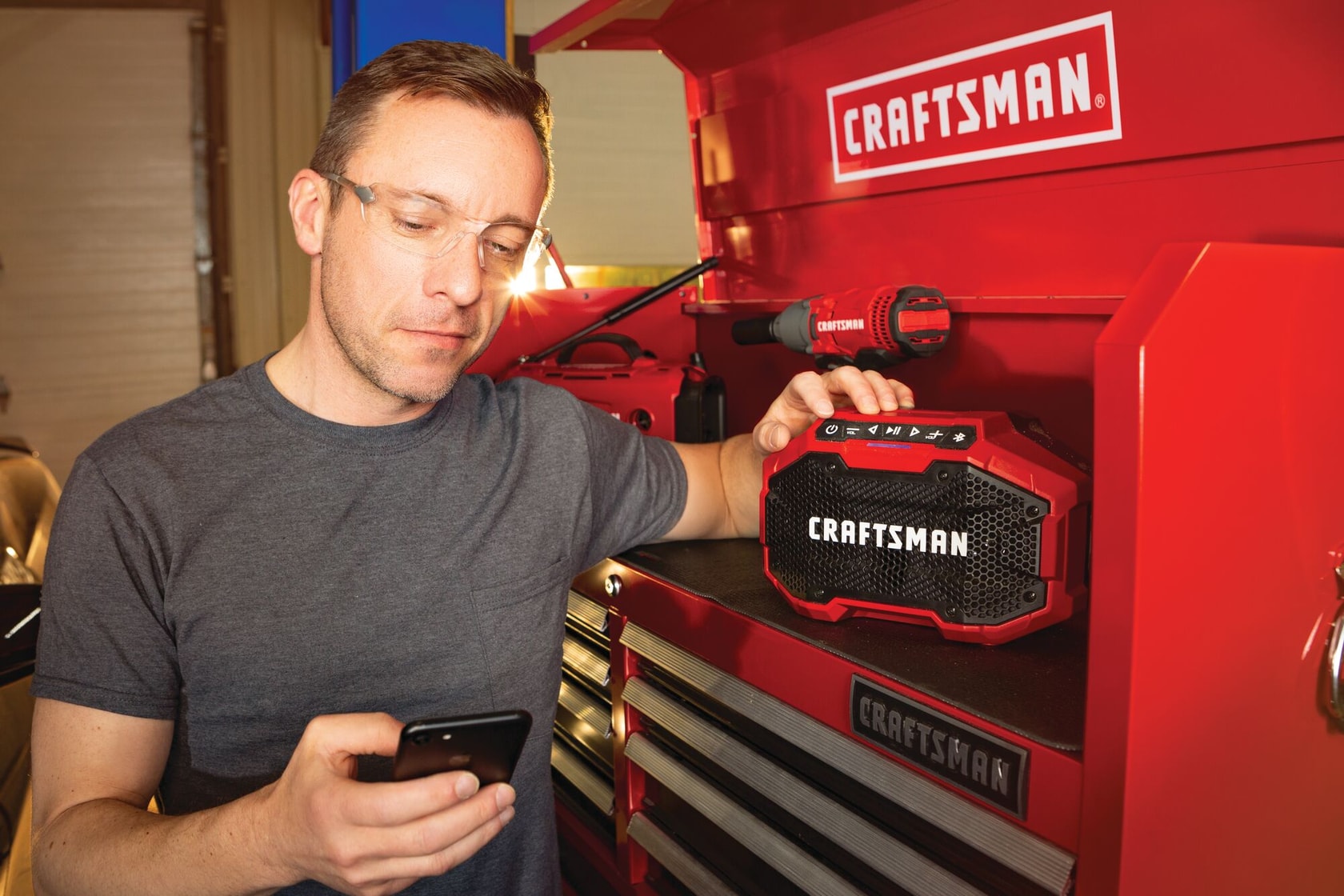 20 volt cordless bluetooth speaker being used by a person to connect a smart phone to stream music.