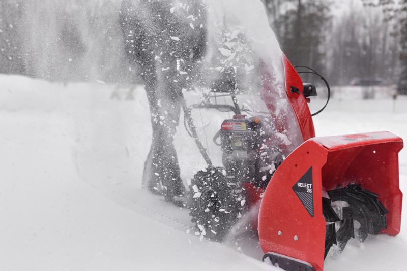 CRAFTSMAN Select 26 Snowblower zoomed in clearing snow from driveway trees in background