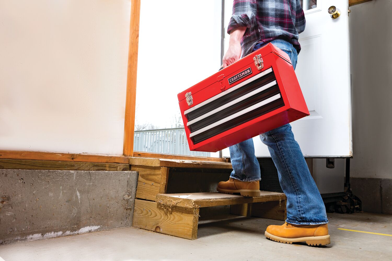 Portable 20 and 5 tenths inch Ball bearing 3 Drawer Red Steel Lockable Tool Box being carried by person towards work site.