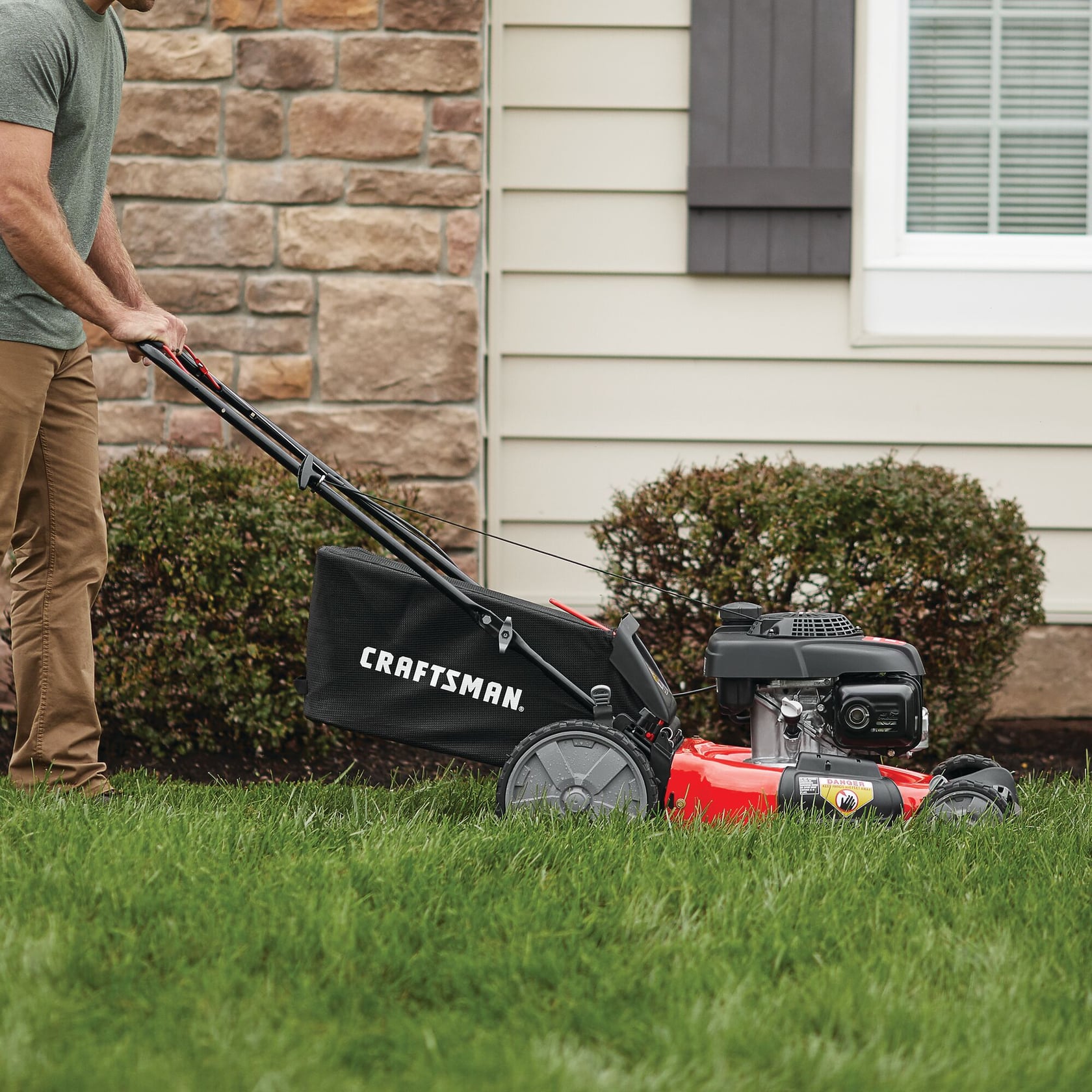 Photo of Craftsman lawn mower SKU CMXGMAM1125500 in use on grass, black bag and red body visible.