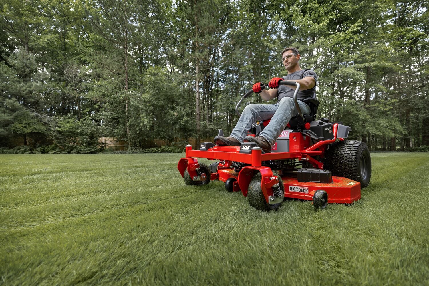 CRAFTSMAN Z7600 Gas Zero-Turn Mower mowing grass with wooded area in the background