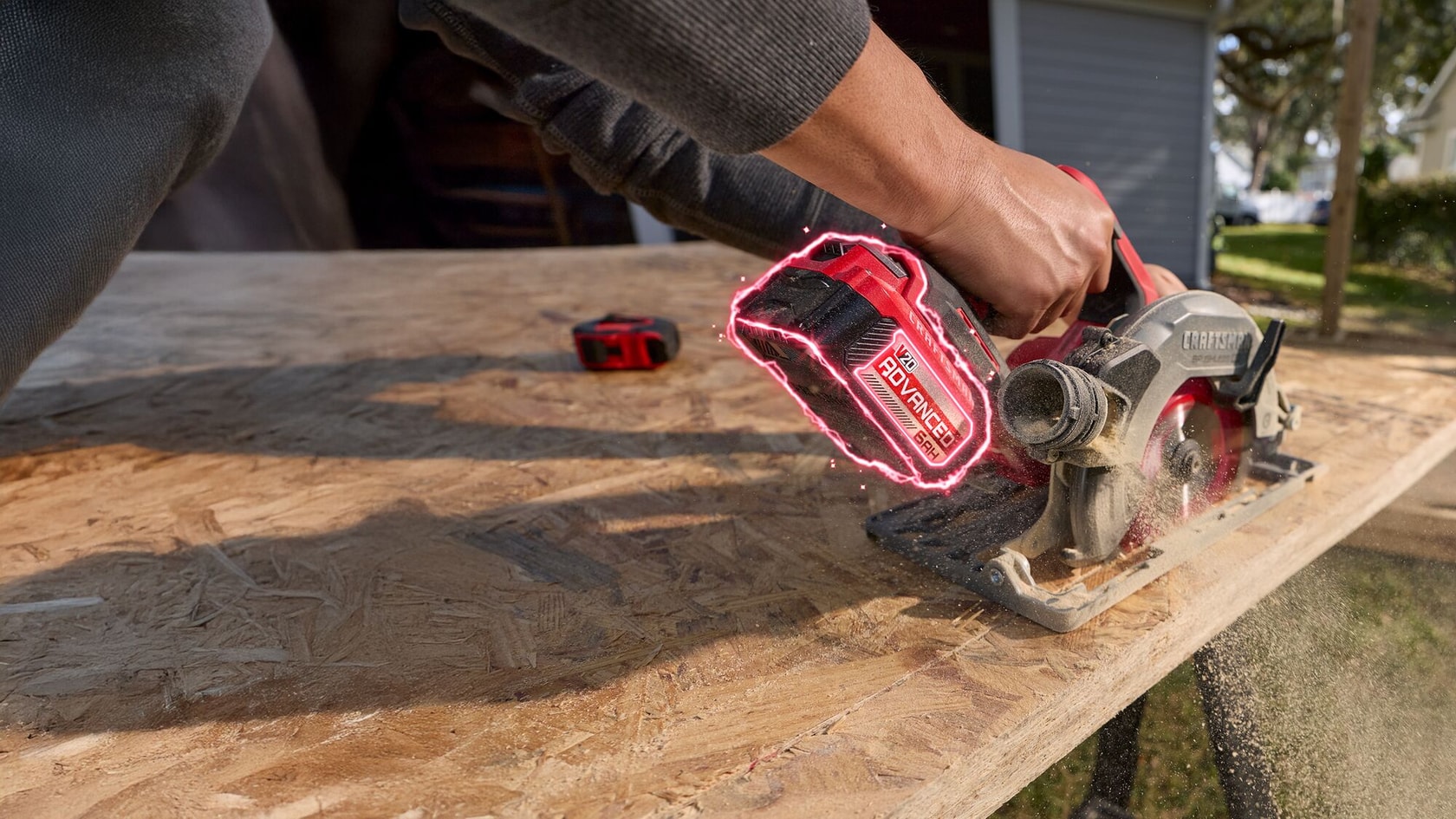 A person using a CRAFTSMAN cordless circular saw with a 20V lithium-ion battery to cut a sheet of wood outdoors.