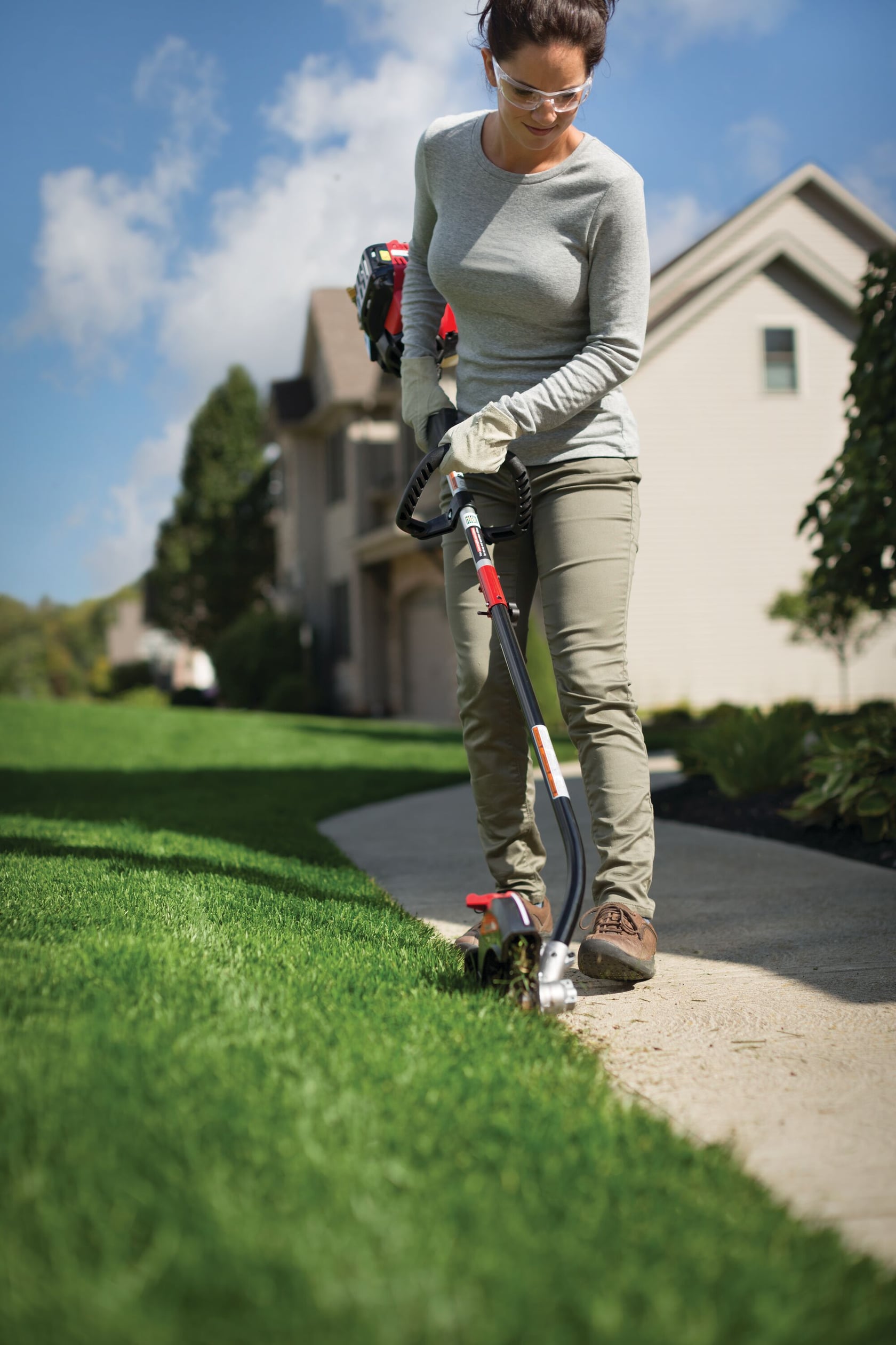 Photo of CRAFTSMAN lawn edger SKU 41BJEA-C902 being used to trim grass along a sidewalk in a residential yard.
