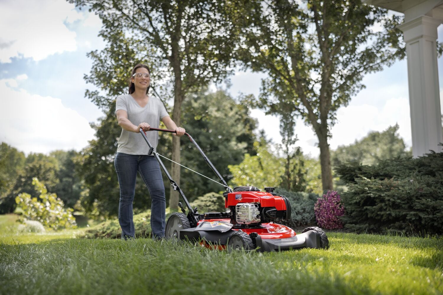 CRAFTSMAN 140cc Push Mower in side view mowing the backyard lawn with maroon shirt