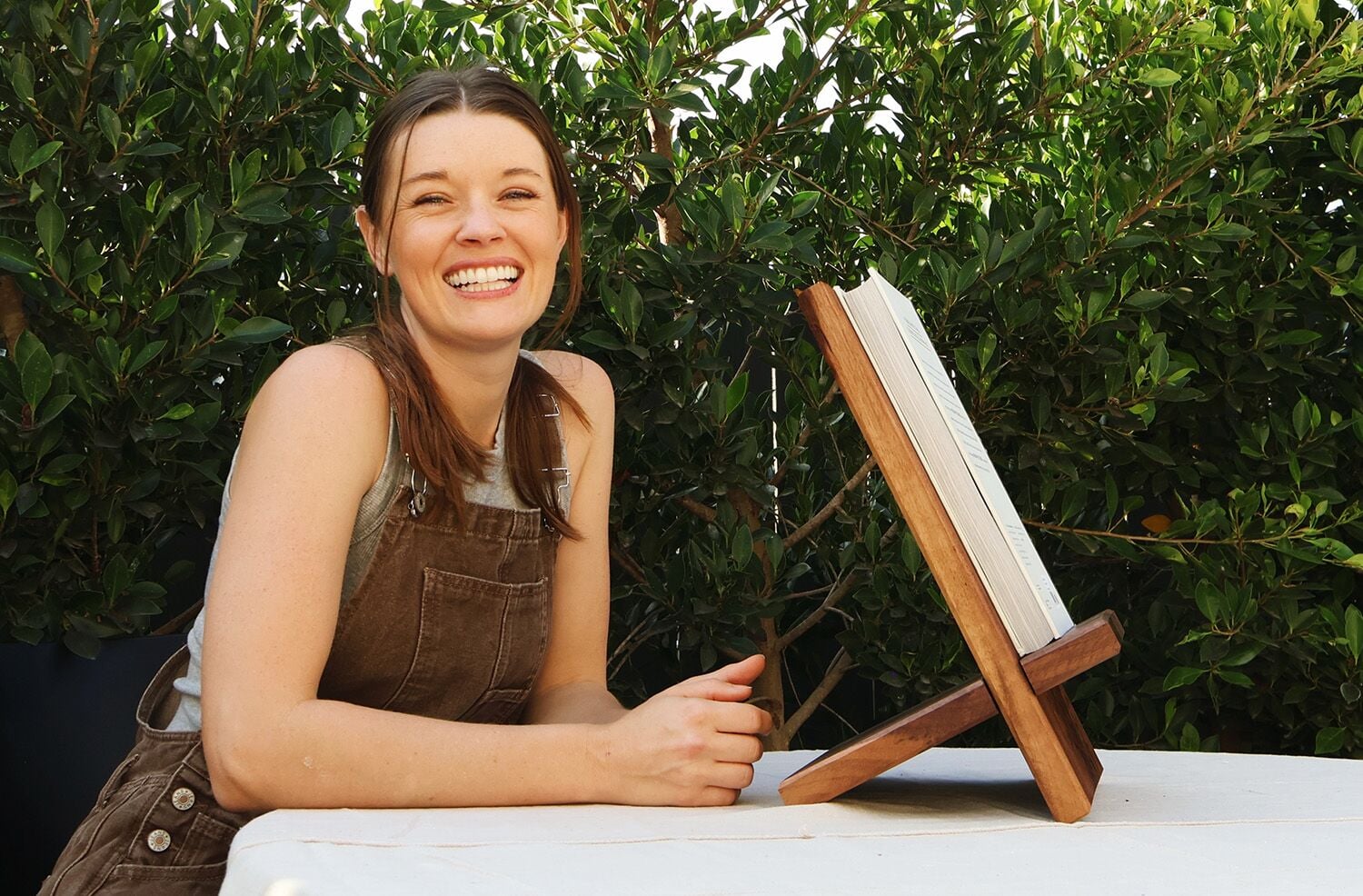 Woman smiling beside cook book stand made of wood