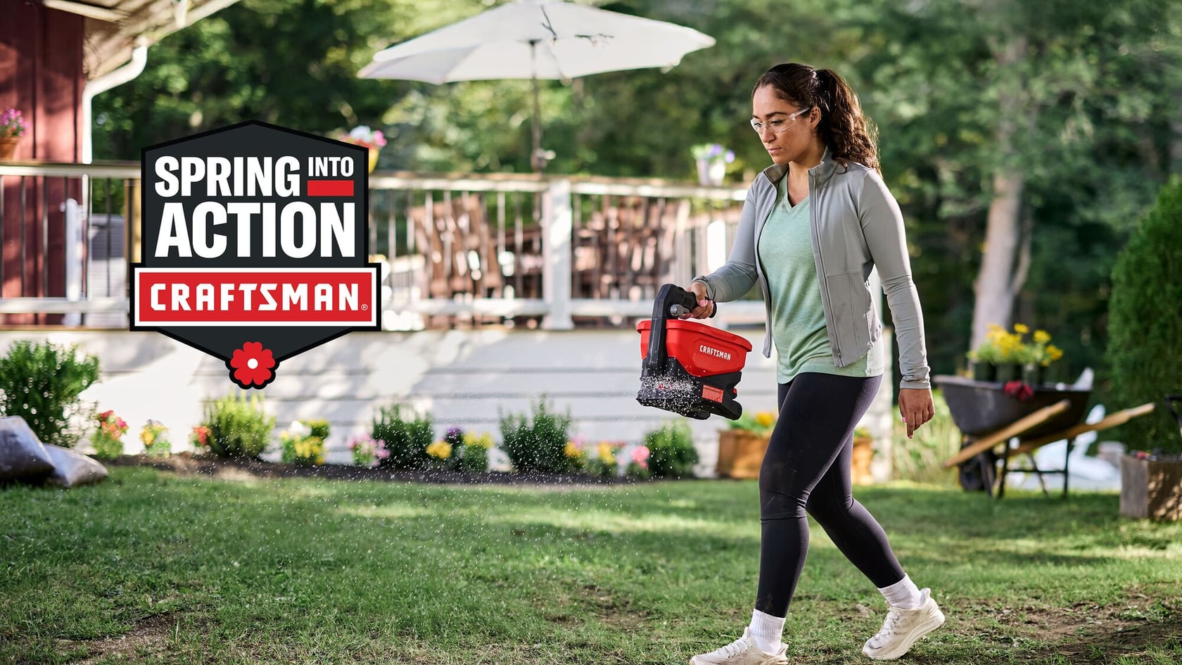 Photo of person spreading lawn seed with CRAFTSMAN handheld spreader CMCOE300B outdoors near a porch, spring setting.