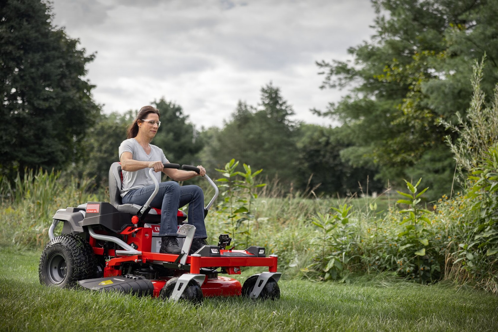 Photo of Craftsman zero-turn lawn mower CMCRM233401 in use outdoors, red and black, cutting grass.