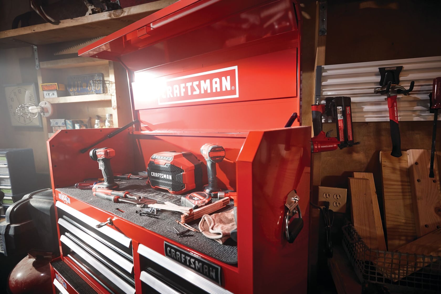Photo of Craftsman red tool chest model CMST24060RB with open lid, power tools and accessories on top in a workshop.