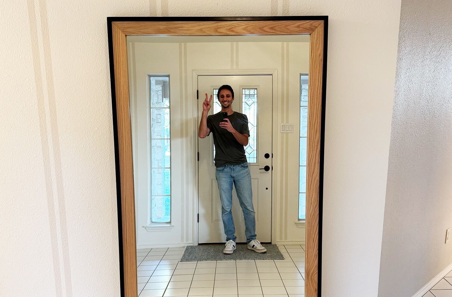 A couple takinga picture in a full length mirror with wooden edges