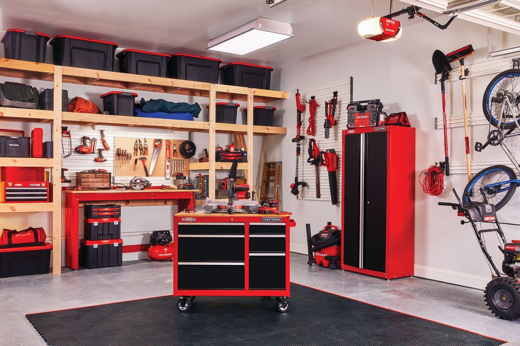 Various tools and gadgets mounted on Versa Track 5 and 5 tenths inch White Composite Multipurpose Storage Rail System installed on wall of garage containing tools cabinets and storage chests stacked on wooden racks.