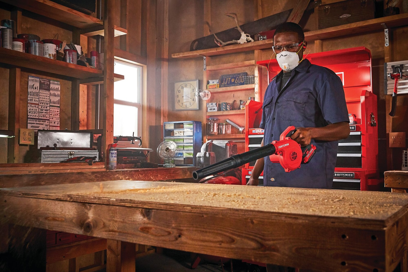 Cordless compact blower being used for blowing away wood dust.
