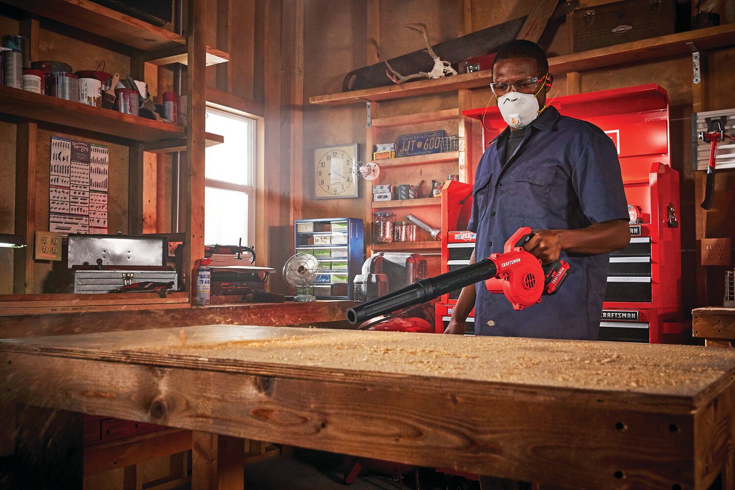 Cordless compact blower being used for blowing away wood dust.