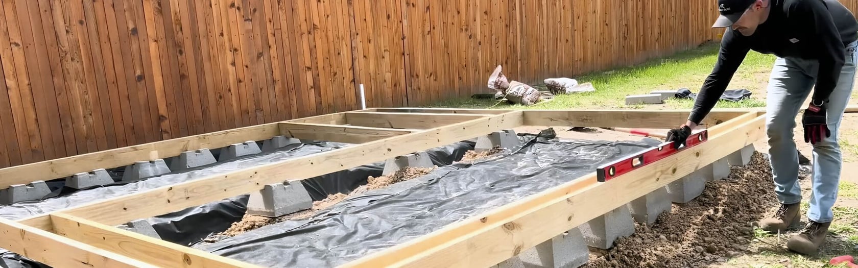 CRAFTSMAN level tool being used to check alignment of wooden foundation frame on cinder blocks, outdoor setting, BrandWebsites.