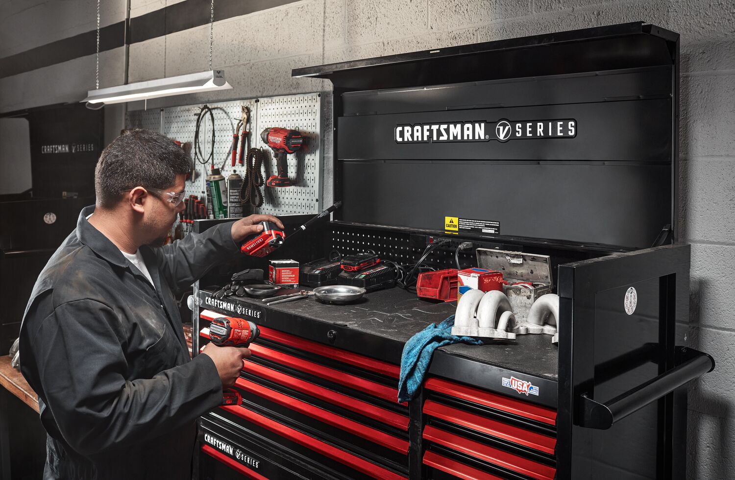 Mechanic working in automotive shop filled with various CRAFTSMAN V-Series™ storage and tools