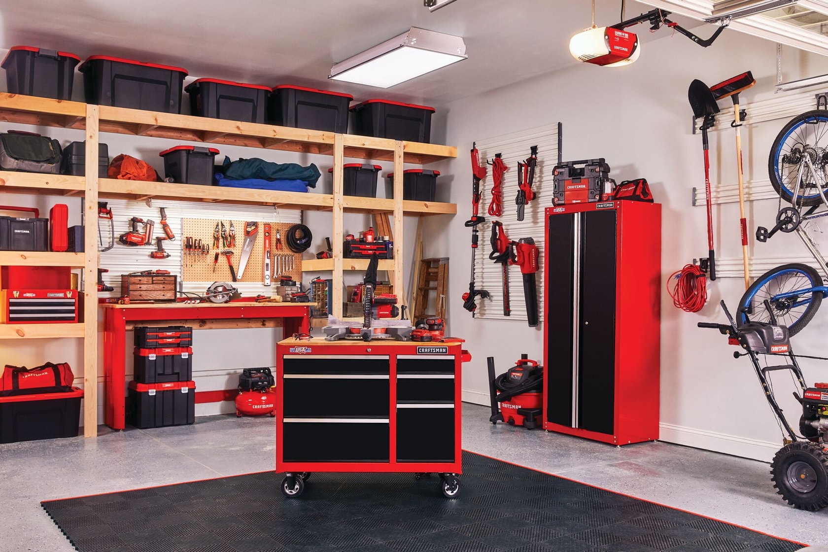 Various tools and gadgets mounted on Versa Track 5 and 5 tenths inch White Composite Multipurpose Storage Rail System installed on wall of garage containing tools cabinets and storage chests stacked on wooden racks.