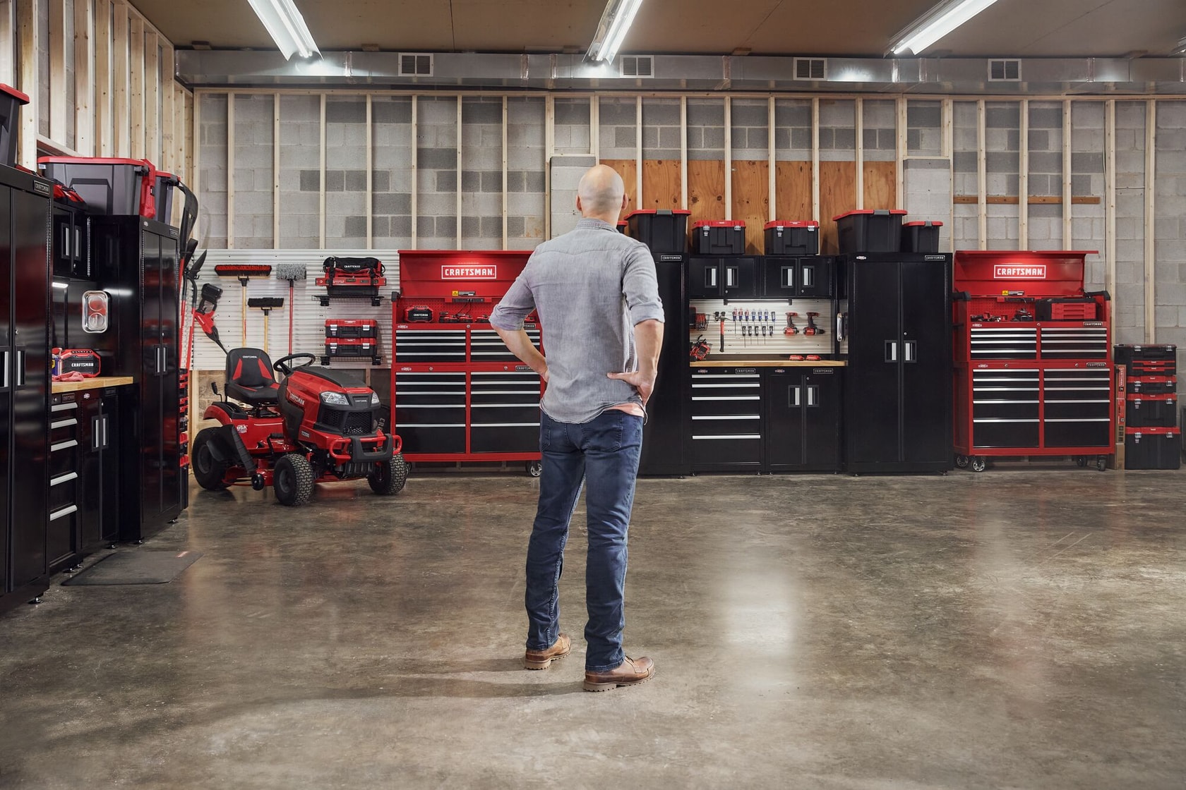 Man standing admiring his garage filled with power tools, storage, outdoor products