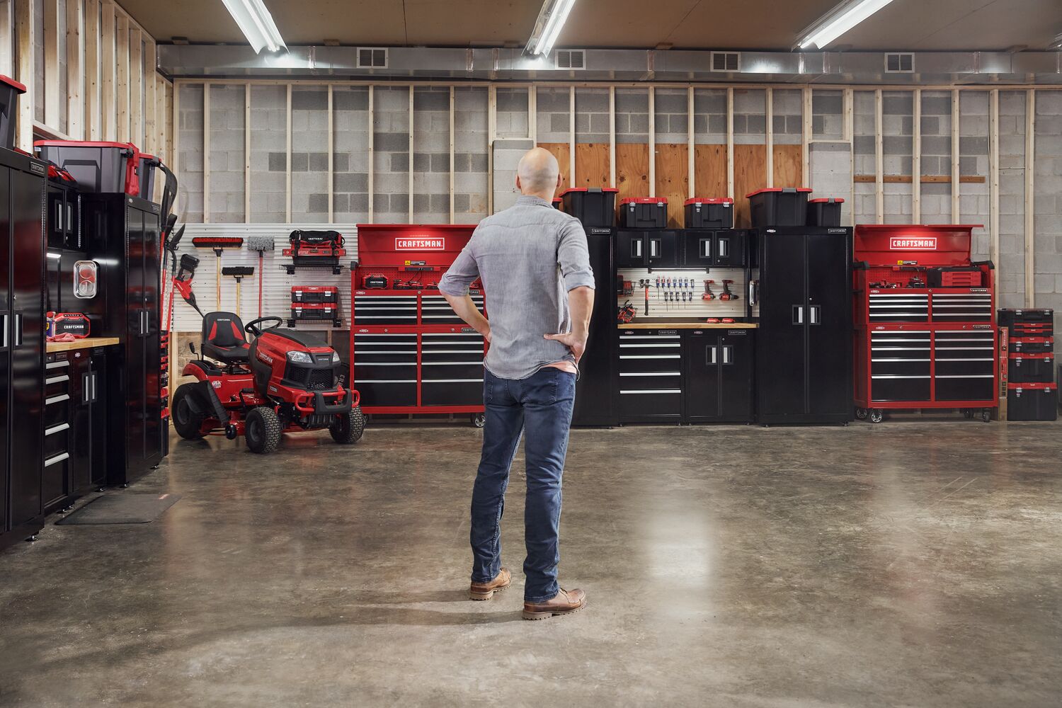 Man standing admiring his garage filled with power tools, storage, outdoor products